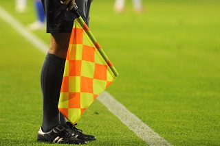 Referee with flag in hand on football pitch