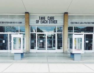 Building with sign above door saying 'Take care of each other'