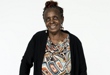 Elderly Black woman in black cardigan with patterned top and earrings