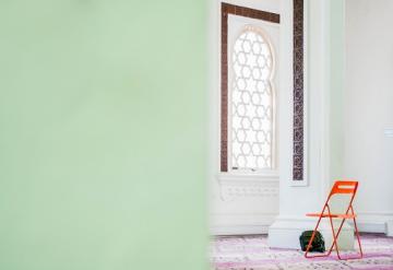 Mosque with mint green walls and orange chair.